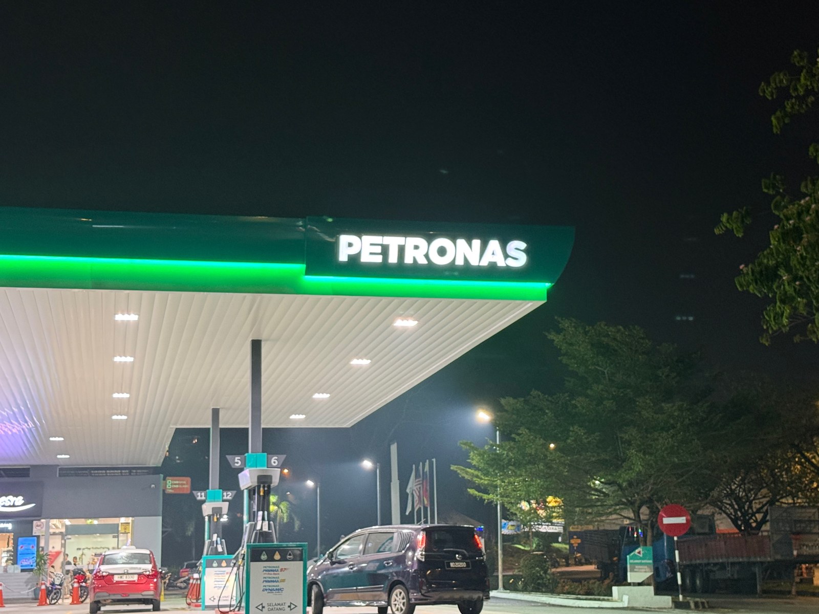 ATHH green tube installed along the canopy edge of a Petronas station at night — wide shot
