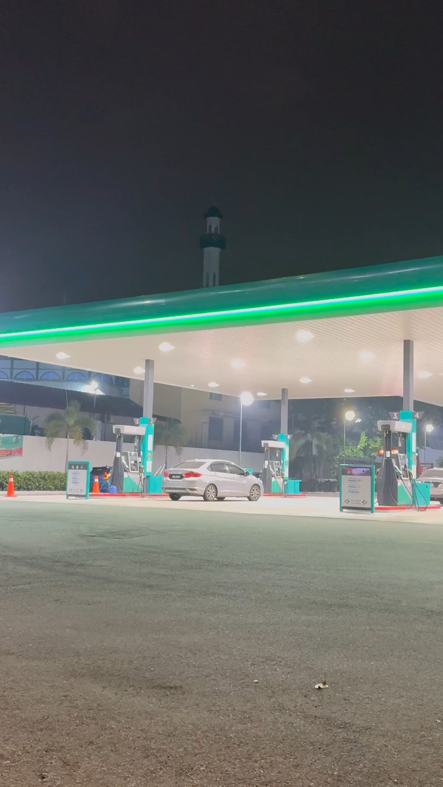 Petronas petrol station at night with the ATHH green tube tracing the canopy edge