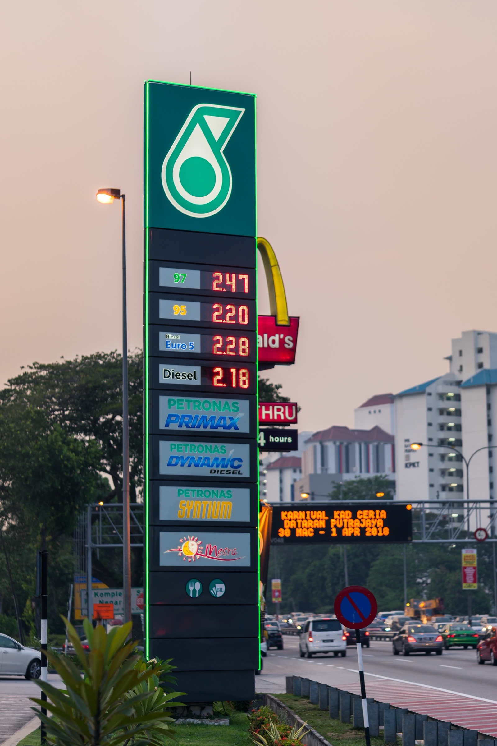 Petronas monolith at dusk with every fuel price lit in red — 97, 95, Diesel Euro 5 and Diesel