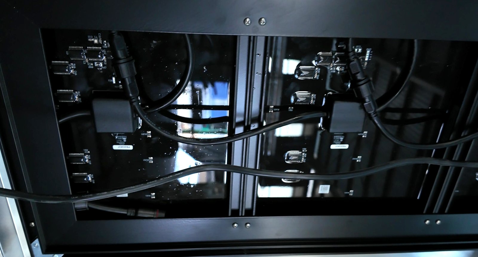 Cabinet opened from the rear — LED driver boards, plugged IP connectors and looped cabling mounted inside the aluminium frame
