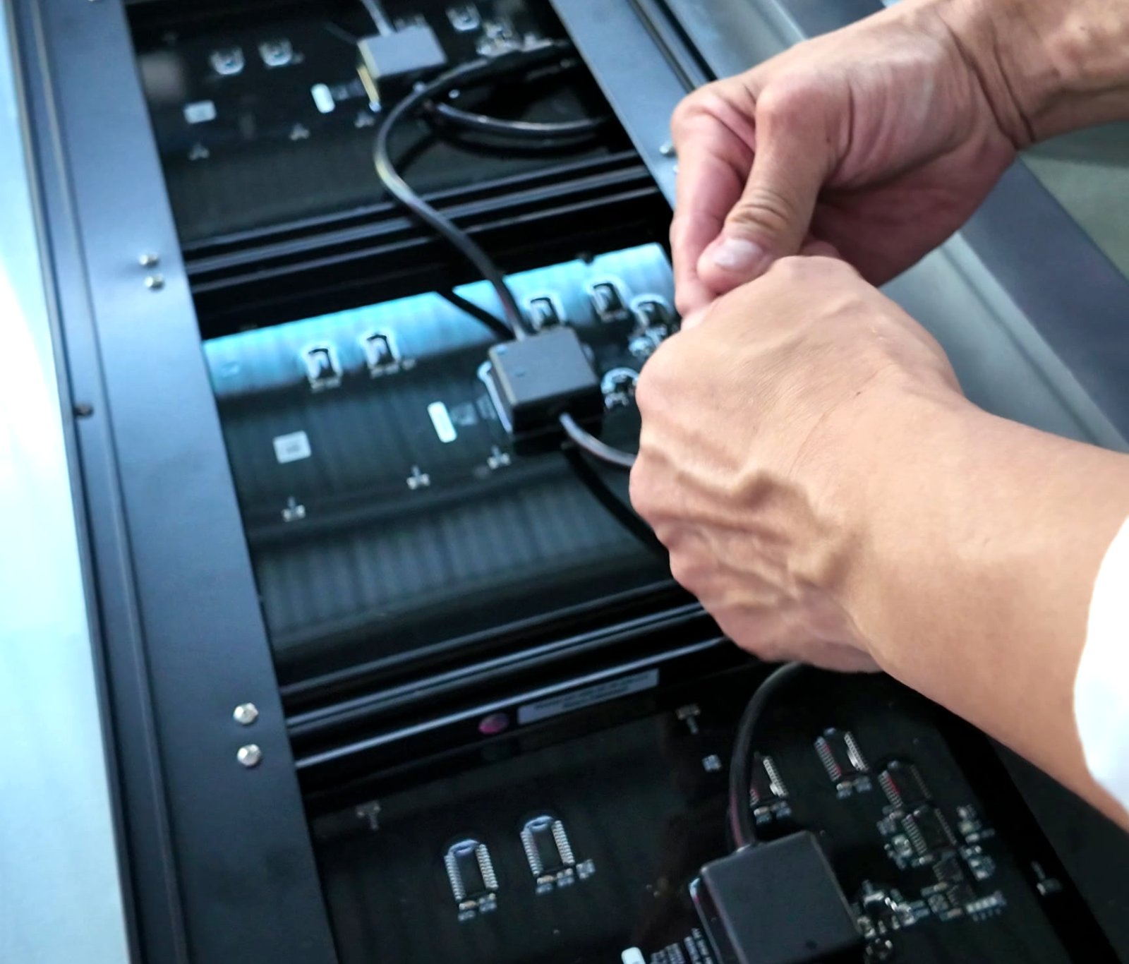 Two hands seating a plug-in connector onto a digit module inside the opened frame