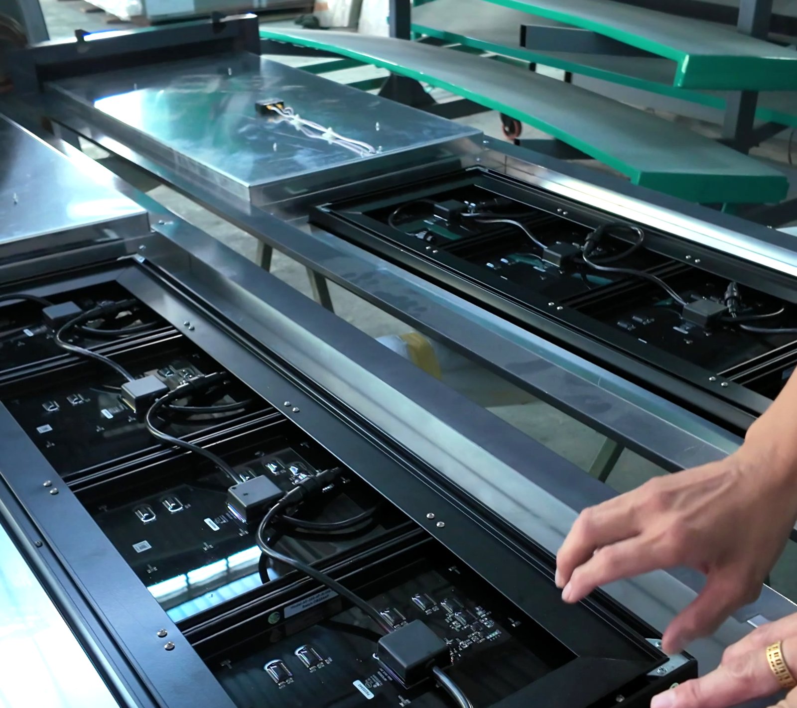 Opened display frames laid on a rack with the digit modules and their cabling exposed, hands working at the frame edge